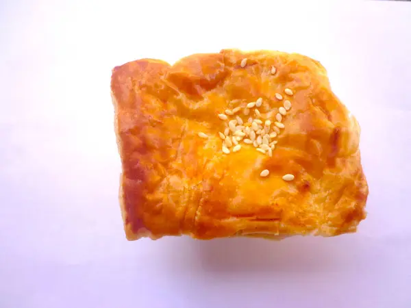Beyaz arka planda susamlı puf böreği..