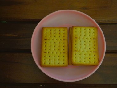 Küçük bir tabak ve ahşap arka planda lezzetli peynirli bisküviler..