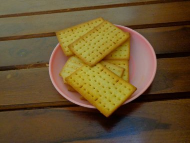 Küçük bir tabak ve ahşap arka planda lezzetli peynirli bisküviler..