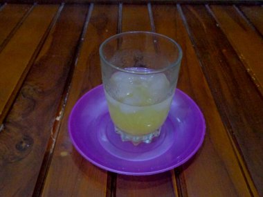 İçi ferahlatıcı portakal buzu ve ahşap arka planla dolu küçük bir bardağın yakın çekimi..