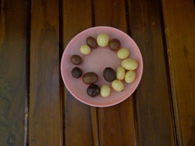 Bademlerle dolu çikolataya odaklan. Küçük bir tabakta, ahşap bir arka planda..