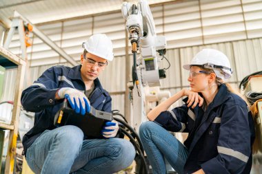 Robot mühendisi fabrika deposunda modern robotik kolun bakımı üzerinde çalışıyor.