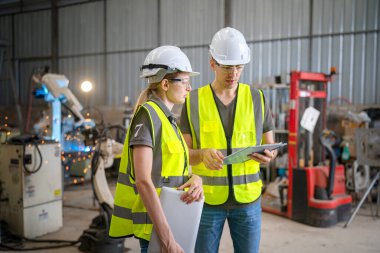 Robot mühendisi fabrika deposunda modern robotik kolun bakımı üzerinde çalışıyor.