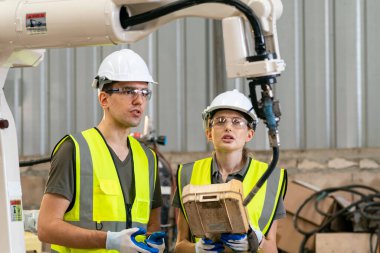 Robot mühendisi fabrika deposunda modern robotik kolun bakımı üzerinde çalışıyor.