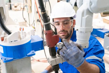 Robot mühendisi fabrika deposunda modern robotik kolun bakımı üzerinde çalışıyor.