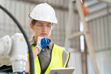 Robot mühendisi fabrika deposunda modern robotik kolun bakımı üzerinde çalışıyor.
