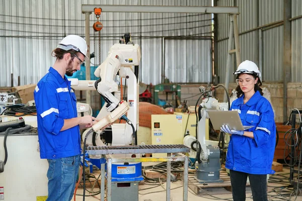 stock image Robotics engineers working on maintenance of modern robotic arm in factory warehouse