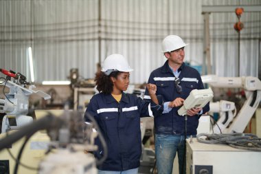 Robot mühendisleri fabrika deposunda modern robotik kolun bakımı üzerinde çalışıyorlar.