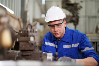 Fabrikada çalışan koruyucu kasklı ve eldivenli bir işçi. 