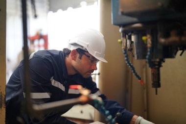 Fabrikada çalışan koruyucu kasklı ve eldivenli bir işçi.