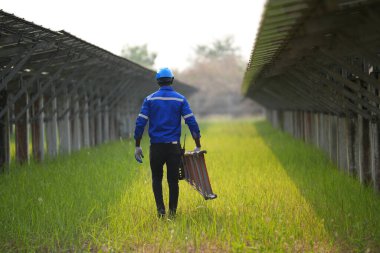 Fotovoltaik bir çiftlikte çalışan elektrik mühendisi, güneş enerjisi endüstrisindeki aletlerle kontrol ve bakım ekipmanlarını kontrol ediyor..