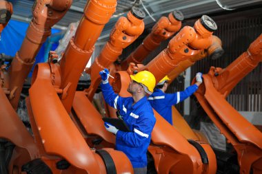 Mühendisler, akıllı fabrika otomotiv endüstrisindeki otomatik silah makinelerinin kaynak ve kontrol sistemlerini kontrol ediyorlar. Dijital üretim operasyonu. Sektör 4.0