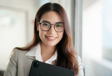 Gözlüklü gülümseyen iş kadınının kameraya baktığı ön manzara.