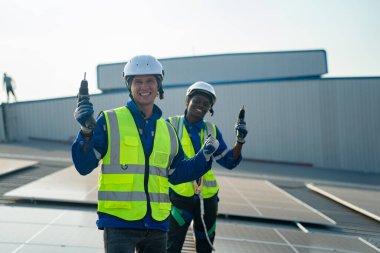 Teknoloji güneş pili, mühendislik servisi fabrikanın çatısında güneş pili kurulumunu kontrol ediyor. teknisyen güneş panellerinin bakımını kontrol ediyor