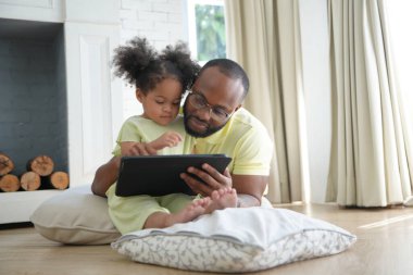 Babası tablet tutan mutlu bir Afrikalı Amerikalı kız. 