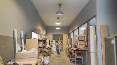 Genç bir kadının küçük işleri. Mobilya atölyesinde yürüyen genç ve güzel bir bayan işçi.