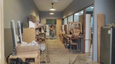 Genç bir kadının küçük işleri. Mobilya atölyesinde yürüyen genç ve güzel bir bayan işçi.