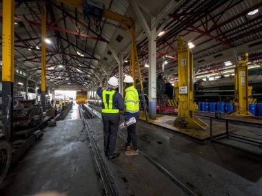 Üniformalı ve kasklı bir erkek işçi fabrikada vinç kullanıyor. Endüstriyel üretim, metal mühendisliği, güç makineleri üretimi