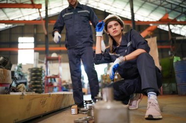 Young successful technician or repairman of industrial machines in safety helmet and workwear standing in large garage or workshop