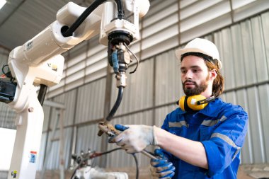 Robot mühendisi fabrika deposunda modern robotik kolun bakımı üzerinde çalışıyor.