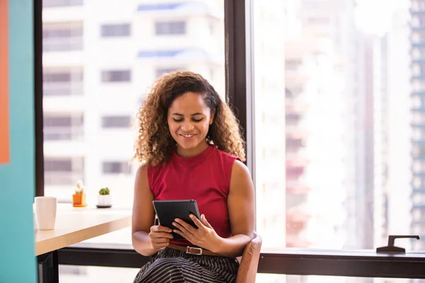 Portrait of happy multiethnic businesswoman using digital tablet in agency