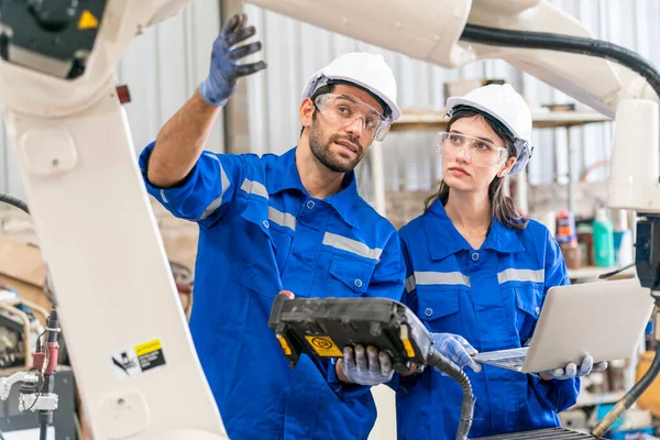 stock image Robotics engineers working on maintenance of modern robotic arm in factory warehouse