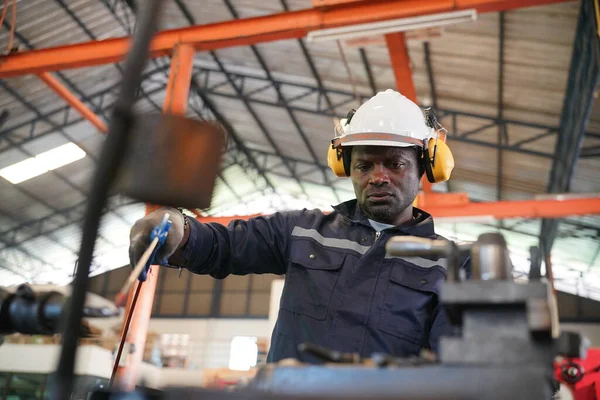 stock image Young successful technician or repairman of industrial machines in safety helmet and workwear  in large garage or workshop