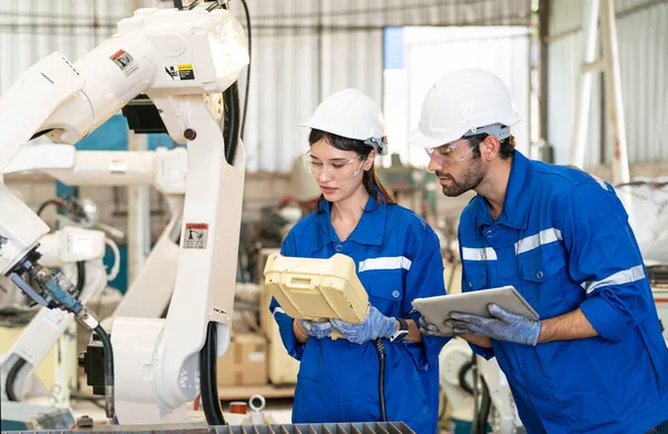 stock image Robotics engineers working on maintenance of modern robotic arm in factory warehouse