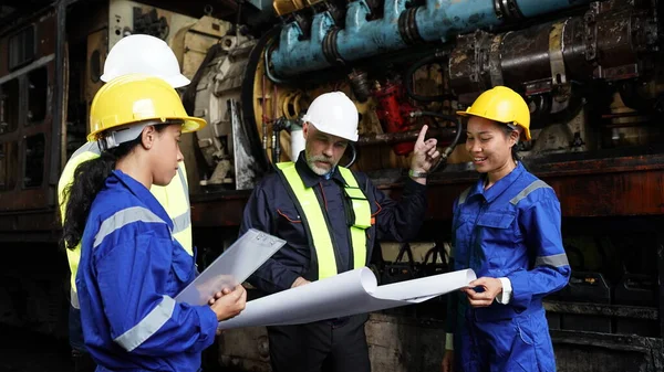 stock image Engineers in discussion in machine maintenance in factory. Group of Industrial Engineers with Blueprint against trains and machinaries industry background. Studying Blueprint with Superior