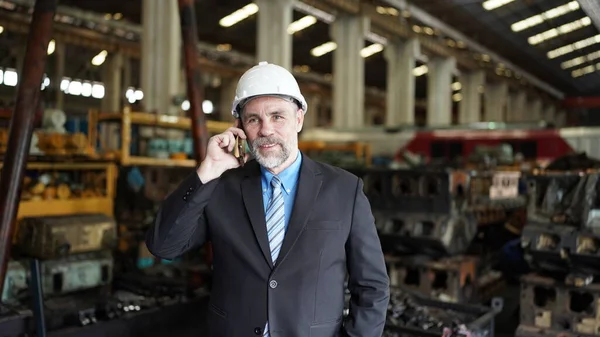Factory manager or businessman in factory warehouse is talking on mobile phone. Factory industry, Business.