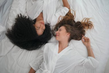 Rahat bir yatak odası bir yatak üzerinde otururken sohbet konuşurken iki güzel kadın