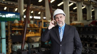 Fabrika müdürü ya da işadamı cep telefonuyla konuşuyor. Fabrika endüstrisi, iş dünyası.