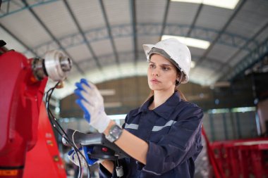 Robot mühendisi fabrika deposunda modern robotik kolun bakımı üzerinde çalışıyor.