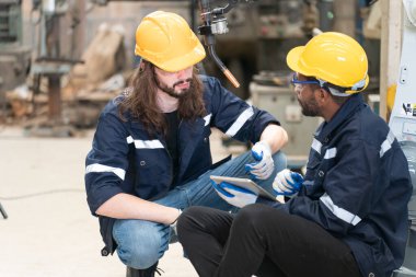 Robot mühendisleri fabrika deposunda modern robotik kolun bakımı üzerinde çalışıyorlar.