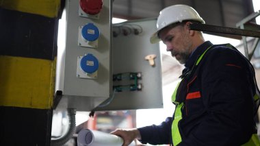 Elektrik santralindeki fabrikada çalışan mühendis. Fabrikadaki elektrik kontrol kutusunun bakımını yapıyor..