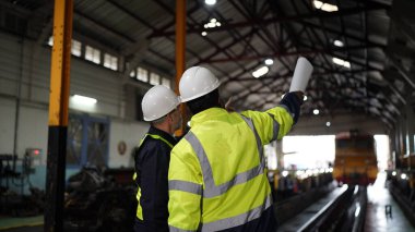 Fabrikadaki makine bakımında mühendisler tartışılıyor. Endüstriyel Mühendisler, tren ve makine endüstrisine karşı.