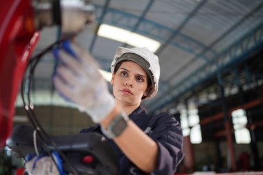 Robot mühendisi fabrika deposunda modern robotik kolun bakımı üzerinde çalışıyor.