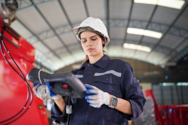 Robot mühendisi fabrika deposunda modern robotik kolun bakımı üzerinde çalışıyor.