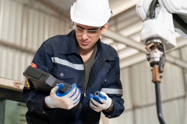 Robot mühendisi fabrika deposunda modern robotik kolun bakımı üzerinde çalışıyor.