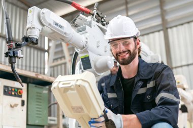 Robot mühendisi fabrika deposunda modern robotik kolun bakımı üzerinde çalışıyor.