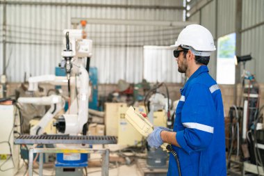 Robot mühendisi fabrika deposunda modern robotik kolun bakımı üzerinde çalışıyor.