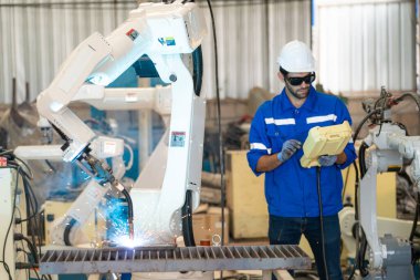 Robot mühendisi fabrika deposunda modern robotik kolun bakımı üzerinde çalışıyor.