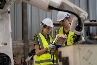 Robot mühendisleri fabrika deposunda modern robotik kolun bakımı üzerinde çalışıyorlar.