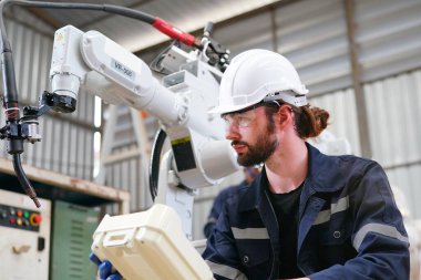 Robot mühendisi fabrika deposunda modern robotik kolun bakımı üzerinde çalışıyor.