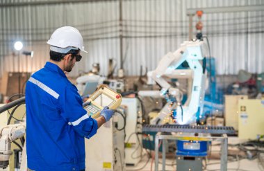 Robot mühendisi fabrika deposunda modern robotik kolun bakımı üzerinde çalışıyor.