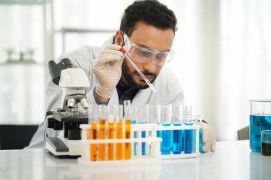 Bir mikrobiyoloji laboratuvarında numune analiz eden bir bilim adamı. Laboratuvar doğal ışıkla aydınlandı.