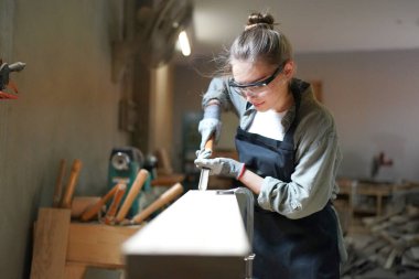 Marangoz DIY atölyesinde çalışan genç ve güzel bir kadın. Küçük işletme sahibi, mobilya fabrikasında çalışan genç bir kadın..