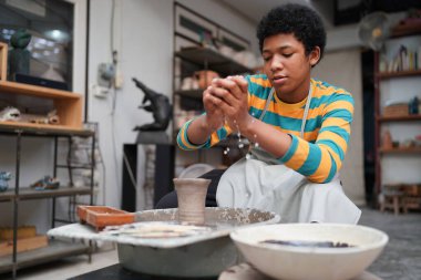 Genç Afro ergen el çömlekçisi çömlek atölyesinde kilden vazo yapıyor.