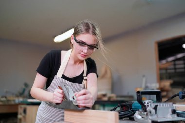 Marangoz DIY atölyesinde çalışan genç ve güzel bir kadın. Küçük işletme sahibi, mobilya fabrikasında çalışan genç bir kadın..