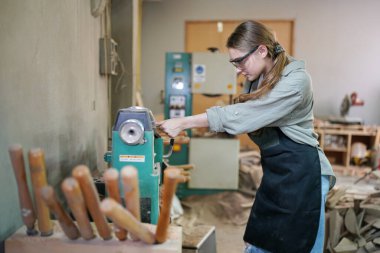 Marangoz DIY atölyesinde çalışan genç ve güzel bir kadın. Küçük işletme sahibi, mobilya fabrikasında çalışan genç bir kadın..